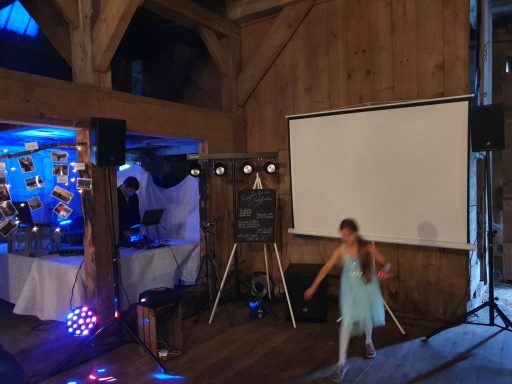 Mädchen tanzt in einem Holzgebäude mit Lichtdekoration und Projektionsleinwand.